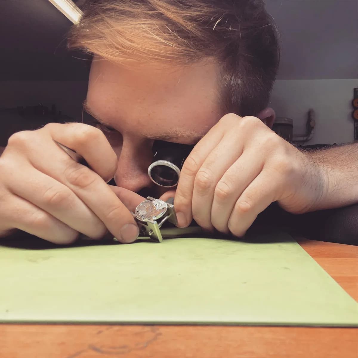 Philip untersucht eine geöffnete Uhr mit der Lupe